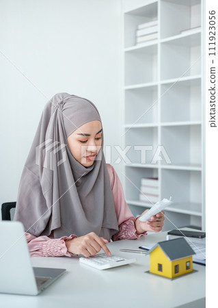 muslim woman with hijab using calculator focus on utility bills calculate check credit card receipt monthly expense muslim woman with hijab using calculator focus on utility bills calculate check credit card receipt monthly expense 111923056