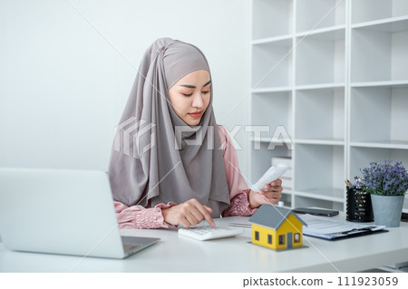 muslim woman with hijab using calculator focus on utility bills calculate check credit card receipt monthly expense 111923059