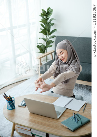 Young business Asian Business muslim woman in hijab using a tablet, Sitting near the window in the living room.  111923067