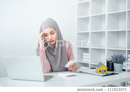 muslim woman with hijab using calculator focus on utility bills calculate check credit card receipt monthly expense 111923071