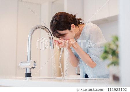 Young woman washing her face at home 111923102