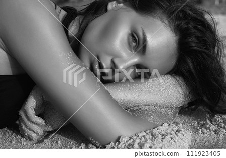 Beautiful young woman in sand on beach 111923405