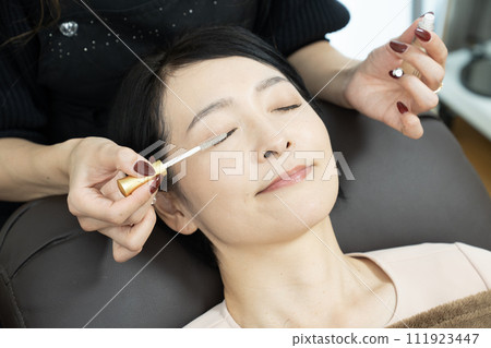 A woman receiving eyelash extensions (photography cooperation: Makanani) 111923447