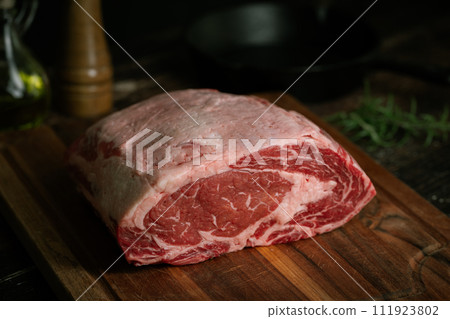chunk of ribeye steak on wooden board 111923802
