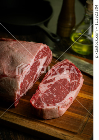 chunk of ribeye steak on wooden board 111923804