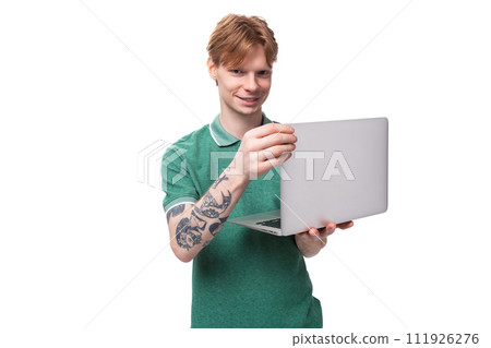 young positive red-haired caucasian guy in a green t-shirt works as an IT specialist and owns a young positive red-haired caucasian guy in a green t-shirt works as an IT specialist and owns a 111926276
