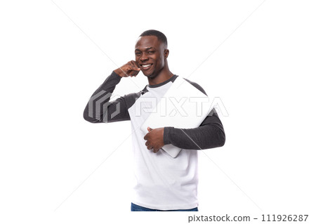 a young American guy dressed in a long-sleeve sweater owns a portable laptop for remote work a young American guy dressed in a long-sleeve sweater owns a portable laptop for remote work 111926287