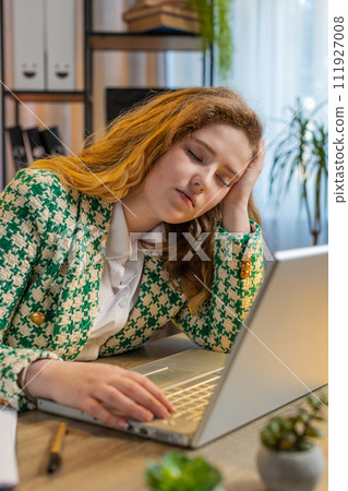 Bored sleepy businesswoman worker working on laptop computer leaning on hand at office desk 111927008