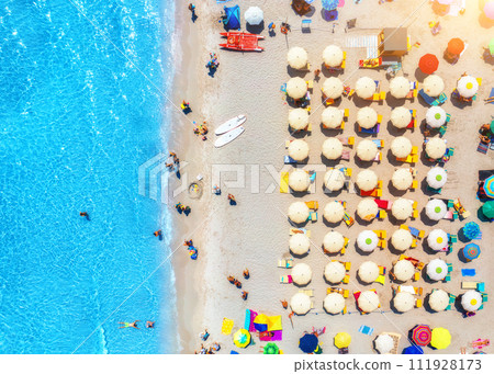 Aerial view of colorful umbrellas on sandy beach and blue sea 111928173
