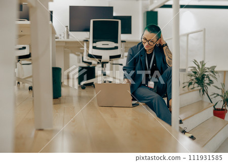 Smiling tattooed female business owner is use laptop sitting on modern coworking background Smiling tattooed female business owner is use laptop sitting on modern coworking background 111931585