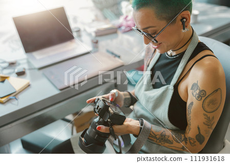 Female designer in eyeglasses looks on shoot in camera screen during working in own design studio 111931618