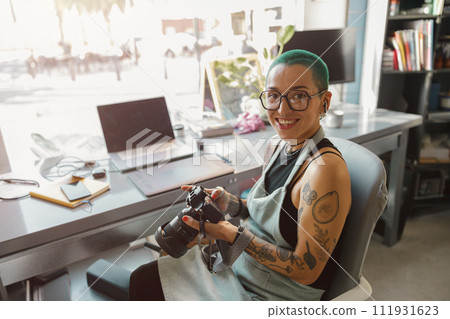 Female designer in eyeglasses use camera during working in own design studio 111931623