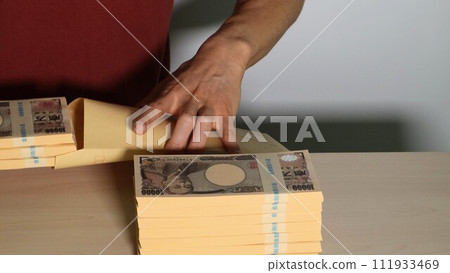 A person who puts a wad of money into an envelope A person who puts a wad of money into an envelope 111933469