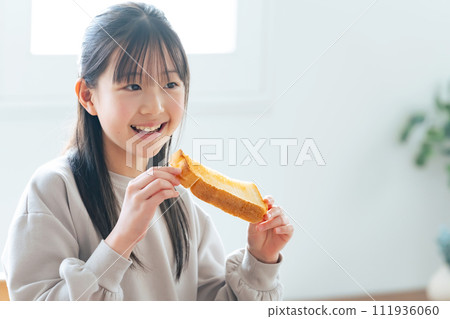 Girl eating toast with a smile 111936060