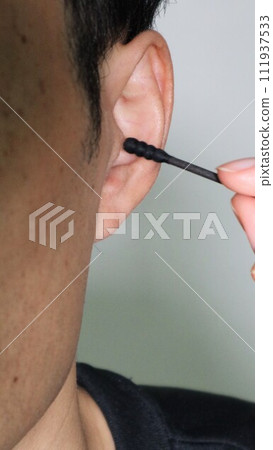 A person cleaning his ears with a cotton swab A person cleaning his ears with a cotton swab 111937533