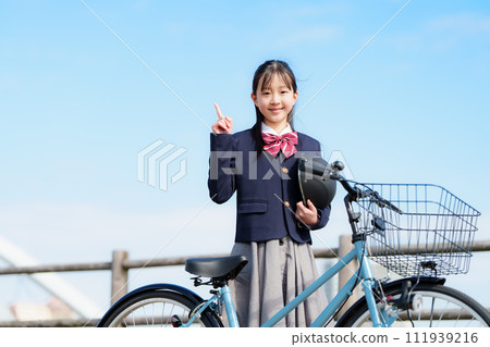 A girl in a uniform walking while pushing a bicycle 111939216