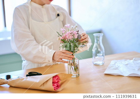 年輕女子在花瓶裡欣賞花 111939631