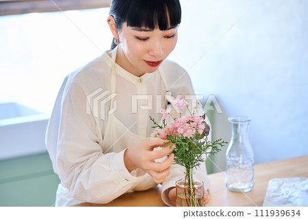 年輕女子在花瓶裡欣賞花 年輕女子在花瓶裡欣賞花 111939634
