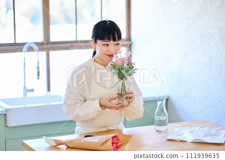 年輕女子在花瓶裡欣賞花 年輕女子在花瓶裡欣賞花 111939635
