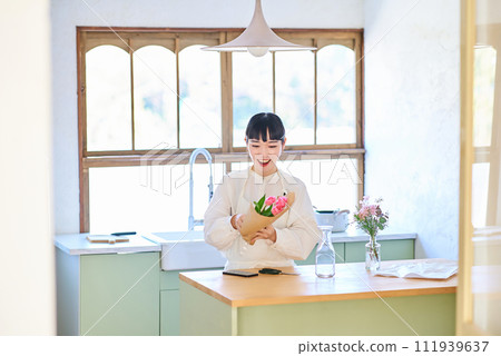 Young woman enjoying flowers in a vase Young woman enjoying flowers in a vase 111939637