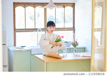 年輕女子在花瓶裡欣賞花 年輕女子在花瓶裡欣賞花 111939638