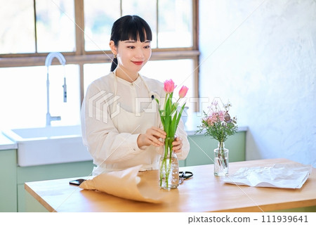 Young woman enjoying flowers in a vase Young woman enjoying flowers in a vase 111939641