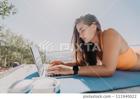 Woman laptop sea. Working remotely on seashore. Happy successful woman female freelancer working on laptop by the sea at sunset, makes a business transaction online. Freelance, remote work on vacation Woman laptop sea. Working remotely on seashore. Happy successful woman female freelancer working on laptop by the sea at sunset, makes a business transaction online. Freelance, remote work on vacation 111940022