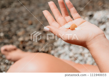 Woman eating milky almond nuts. A young caucasian woman chopping fresh green almond after morning fitness yoga near sea. Only hands are visibly. Healthy vegan food. Slow motion. Close up Woman eating milky almond nuts. A young caucasian woman chopping fresh green almond after morning fitness yoga near sea. Only hands are visibly. Healthy vegan food. Slow motion. Close up 111940033