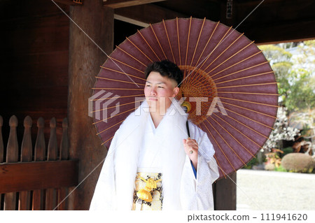 銀色和白色的男士褲裙搭配時尚的長外罩,成年男子穿著鳳紋褲裙,成年儀式外景拍攝 銀色和白色的男士褲裙搭配時尚的長外罩,成年男子穿著鳳紋褲裙,成年儀式外景拍攝 111941620