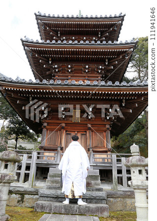 銀色和白色的男士褲裙搭配時尚的長外罩,成年男子穿著鳳紋褲裙,成年儀式外景拍攝 銀色和白色的男士褲裙搭配時尚的長外罩,成年男子穿著鳳紋褲裙,成年儀式外景拍攝 111941646
