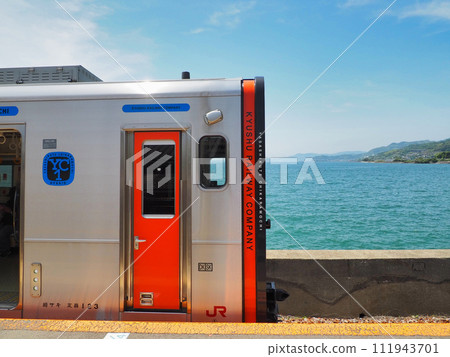 Red train stopping at Chiwata Station platform JR Kyushu Omura Line 111943701