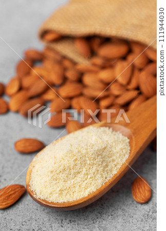 Fresh almond flour in a wooden spoon and almonds Fresh almond flour in a wooden spoon and almonds 111944030