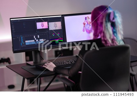 Professional female film editor editing video on his personal computer with two displays in modern video studio Professional female film editor editing video on his personal computer with two displays in modern video studio 111945493
