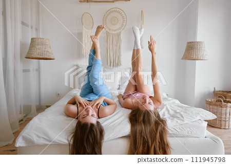 Two young beautiful girl friends on bed enjoying free time together 111945798