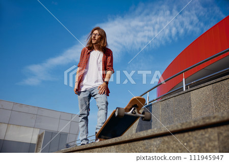 Active energetic stylish hipster guy riding skateboard on city street 111945947