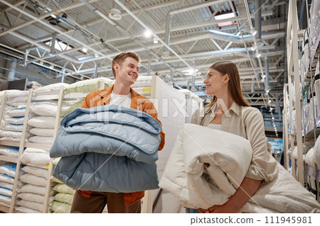 Happy young couple buying new bedding blanket for home at linen store Happy young couple buying new bedding blanket for home at linen store 111945981