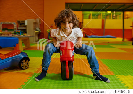 Little boy child playing at playroom riding toy motorcycle 111946066