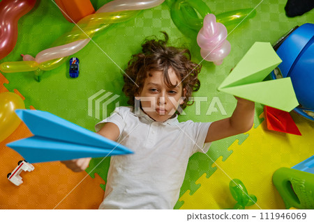 Little boy kid playing paper planes on floor of childcare center 111946069