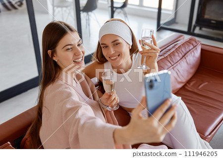 Two woman friends or sisters taking selfie photo on smartphone 111946205