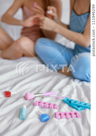 Two young girls painting their nails closeup, teenagers enjoying sleepover party 111946299