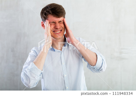Young man experiencing acute headache in living room 111948334
