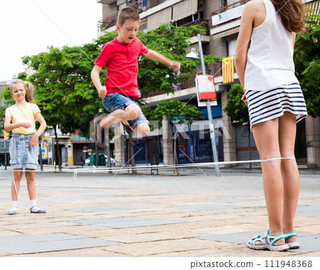 Boy jumps over the rope on the sidewalk in the city in summer Boy jumps over the rope on the sidewalk in the city in summer 111948368