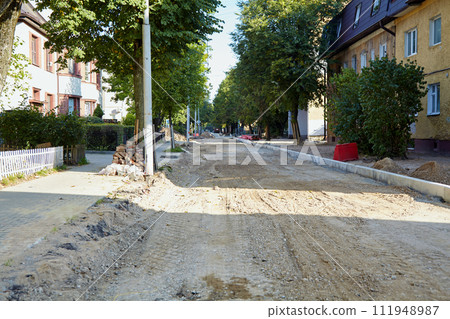 Dirt road with removed asphalt in the city. Construction repair site of road works 111948987