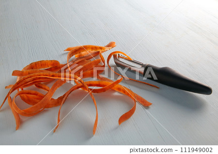 Knife for peeling vegetables and peeling carrots on a light wooden table 111949002