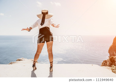Woman sea hat. Business woman in yellow hat freelancer working over blue sea beach. Girl relieves stress from work. Freelance, digital nomad, travel and holidays concept 111949640