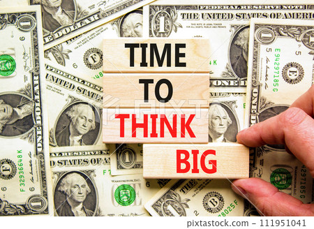 Time to think big symbol. Concept words Time to think big on beautiful wooden block. Beautiful dollar bills background. Businessman hand. Dollar bills. Business time to think big concept. Copy space. Time to think big symbol. Concept words Time to think big on beautiful wooden block. Beautiful dollar bills background. Businessman hand. Dollar bills. Business time to think big concept. Copy space. 111951041