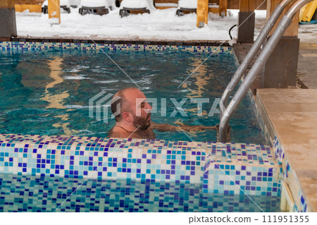 Man enjoying a leisurely swim in a snowcovered swimming pool 111951355
