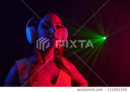 Portrait of young woman in headphones working as dj in night club Portrait of young woman in headphones working as dj in night club 111952148