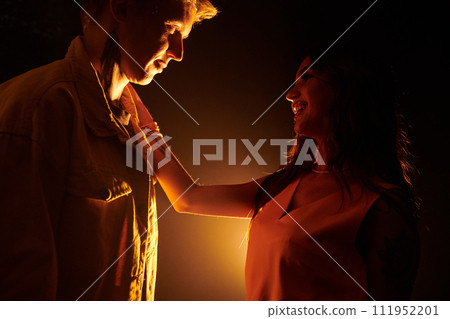 Happy young woman in love putting hand on shoulder of her boyfriend and looking in his eyes 111952201