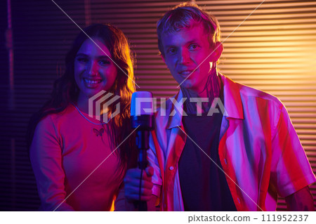 Portrait of smiling duet singing song in microphone at party 111952237